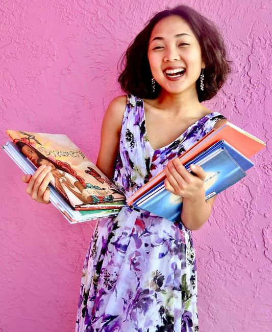 Portrait of Maya Lê, Artist & Elementary School Teacher holding books